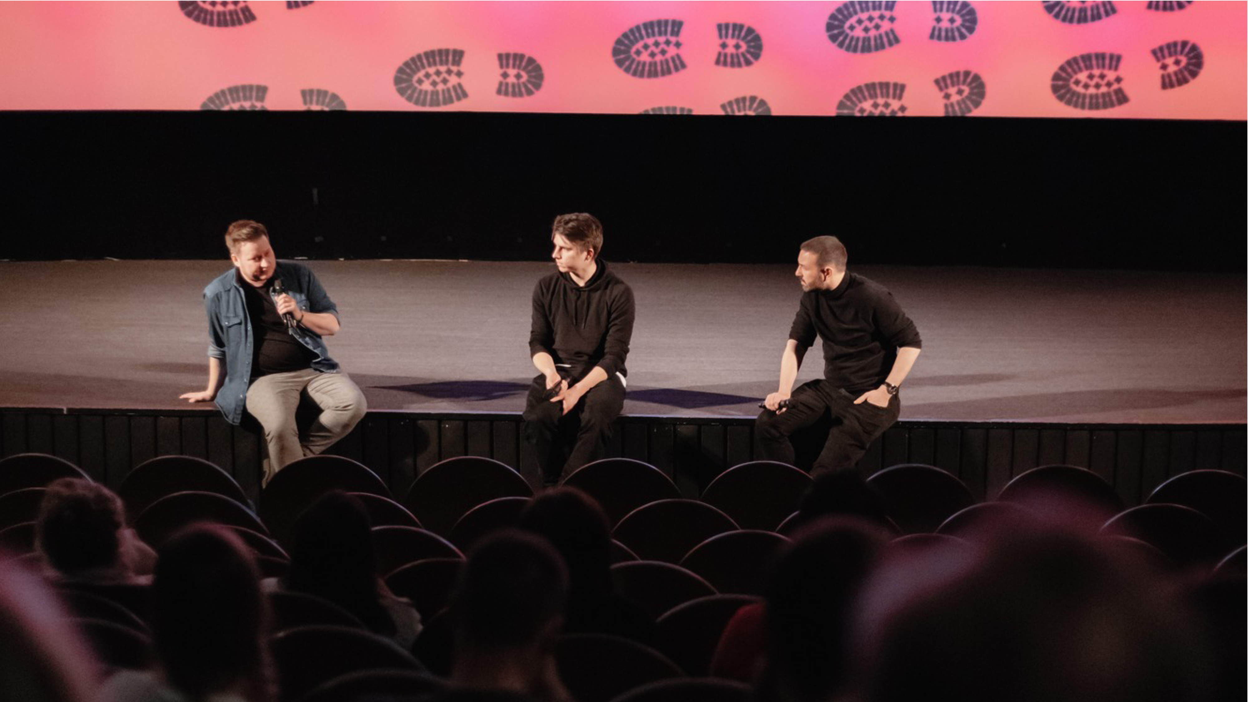 Debata na podiu Tři muži sedí na pódiu a debatují po filmu s diváky.