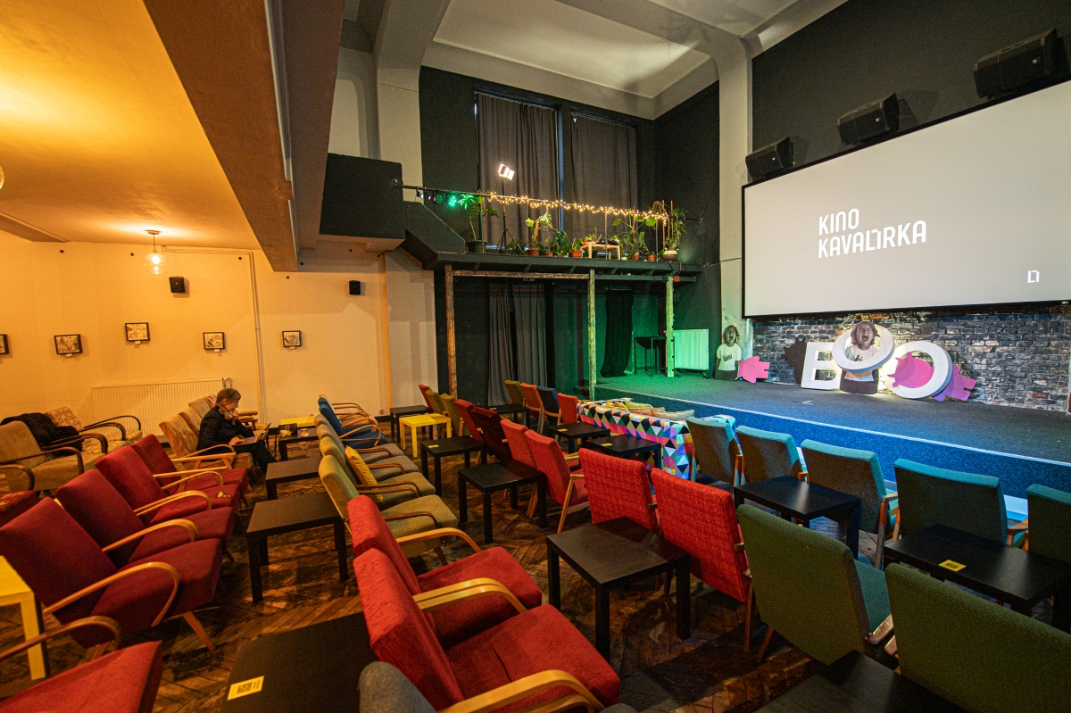Komorní sál Kina Kavalírka s křesílky, stolečky, pohovkou a plátnem.