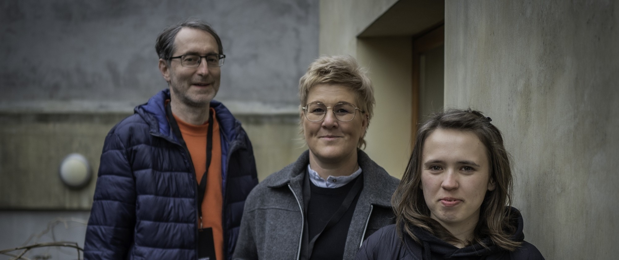 Tři osoby stojí vedle sebe.