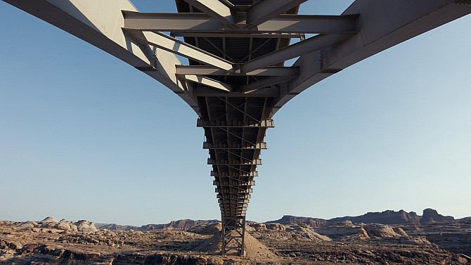 Kovový most focený ze spodu. Vzadu jde vidět vyschlá krajina s horami.