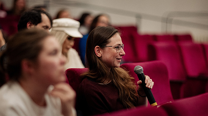 „Co můžu udělat já?“ Otázka, která na debatách Jednoho světa zaznívá nejčastěji Žena sedící v červeném křesle drží mikrofon a pokládá otázku během diskuse. Má brýle a dlouhé hnědé vlasy, kolem ní sedí další účastníci, zatímco pozadí tvoří řady červených sedadel.