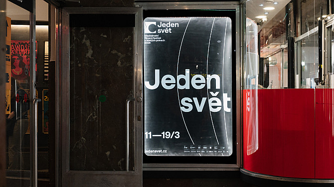 Jeden svět otevírá přihlášky na rok 2027 Plakát festivalu Jeden svět ve výloze v pasáži, na kterém je velký bílý nápis „Jeden svět“ a datum konání. Vedle výlohy je vstup do kina Světozor.
