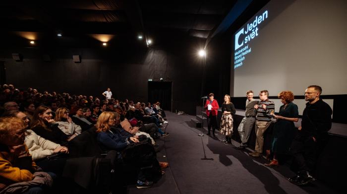 Tipy pro první návštěvu Kinosál plný diváků, naproti nim pod plátnem stojí debatní hosté a jeden z nich mluví do mikrofonu.