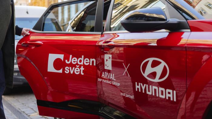 Detail dveří červeného auta s nápisem Jeden svět, Arval a Hyundai.