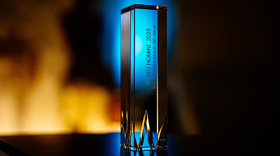 Na stole stojí skleněná cena, na které je vyryto: "Homo Homini 2025, Mikalai Statkevich, Belarus".